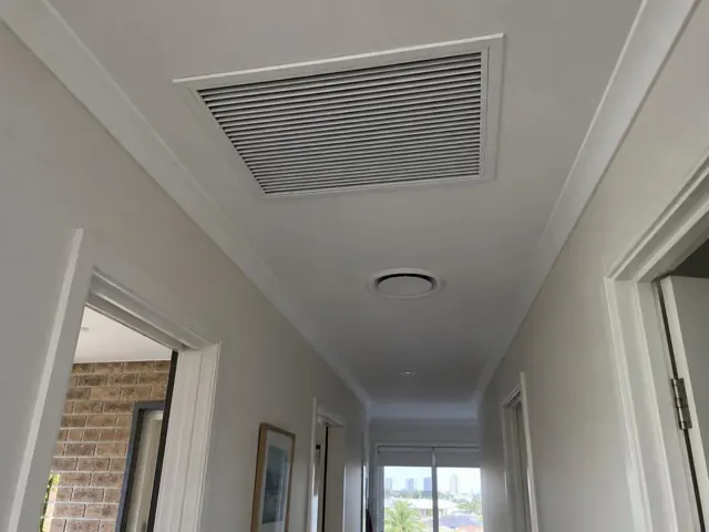 Hallway ceiling with a flush return-air grille and round ceiling outlet in a modern home in Surfers Paradise